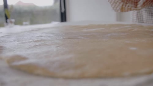 Junge Frau rollt zu Hause Teig für einen Kuchen in der Küche aus. Hausgemachtes Gebäck aus nächster Nähe an einem sonnigen Tag
