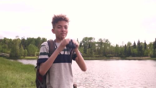 Boy Looking Through Binoculars on River Bank Active