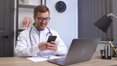 Smiling Doctor Using Phone in Office