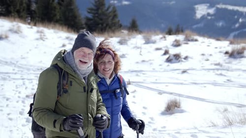 Senior couple hiking in snow covered slovakia mountains smiles at camera
