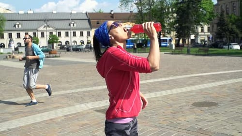 Woman Drinking Isotonic Drink After Jogging In City, Slow Motion