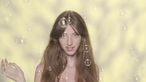 Young Woman with Bubbles in Front of Yellow Background