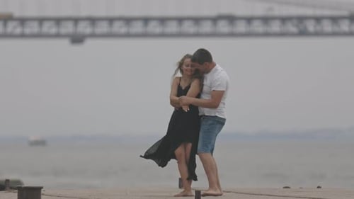 A Romantic Married Couple Dancing on the Pier with a Bridge on the Background