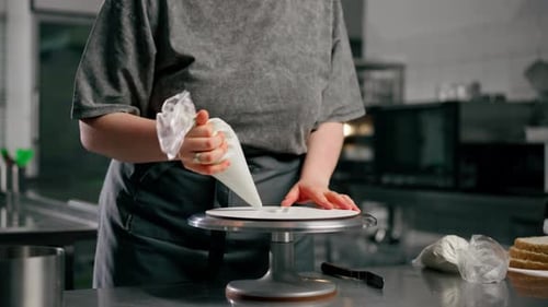 Woman Decorates Layer Cake With White Frosting