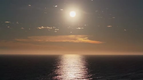 Majestic aerial shot of a beach at sunset, with waves gently rolling under fiery evening skies.
