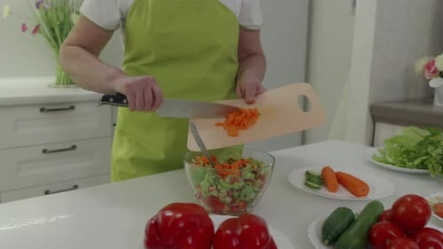 Frau fügt gehackte Karotten zu einem frischen Salat hinzu