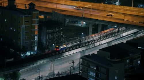Train Gliding Below Overpass At Night