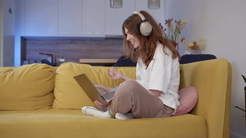 Woman On Couch Video Calling With Laptop And Headphones