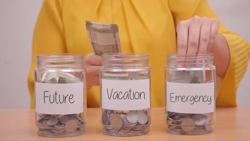 Woman Divides Cash into Savings Jars