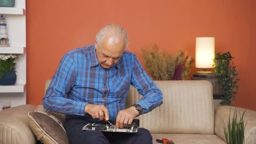 Senior Man Repairs Circuit Board at Home
