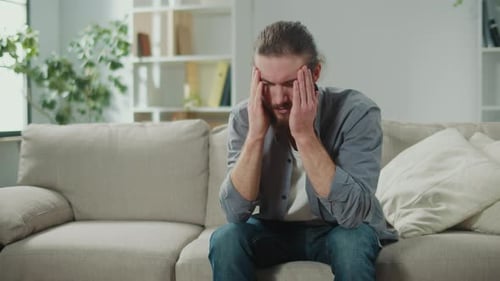 Stressed Man Massaging Temples on Couch