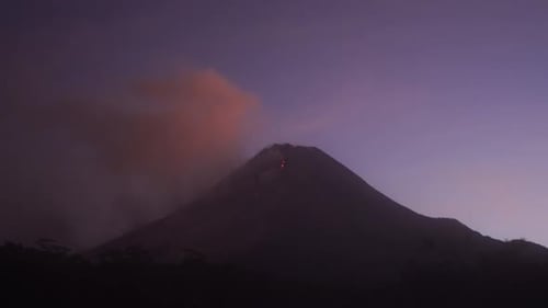 lava incandescente que fluye desde la cima del monte Merapi una noche contra un fondo de cielo púrpura