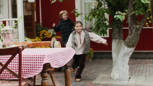 Children Run to Hug Senior Man Outside Farmhouse