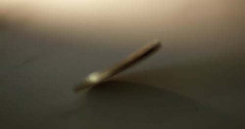 A piece of commemorative golden coin in Thai Baht currency is twirling and slowing down as it lays d