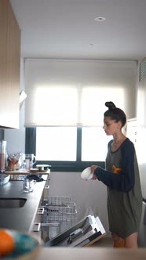 A Woman Organizes Kitchen Cabinets Loads the Dishwasher and Does Chores to Keep Her Home Clean