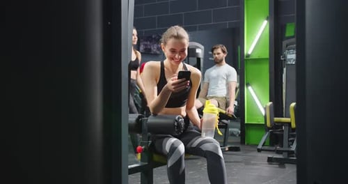 Woman Using Phone at the Gym, Smiling