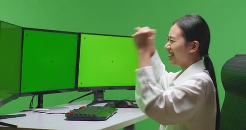 Happy Woman Celebrating While Working With Mock Up Multiple Computer Monitor In Green Screen Studio
