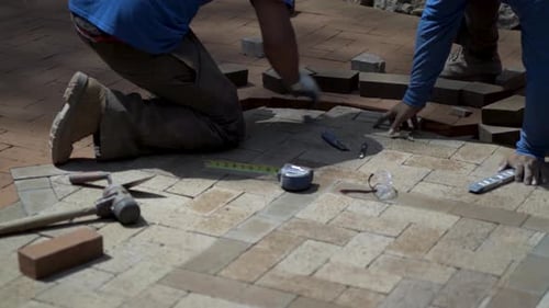 Construction Workers Installing Red Bricks on a Patio