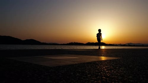 Silhueta de uma criança correndo ao pôr do sol.