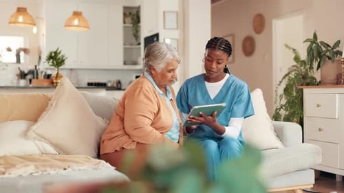 Home Health Aide Consults with Senior on Tablet