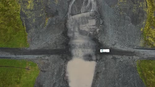 White van crossing muddy river in Iceland travels, aerial downwards view