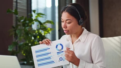 Woman in Headset Showing Financial Report During Video Conference at Office