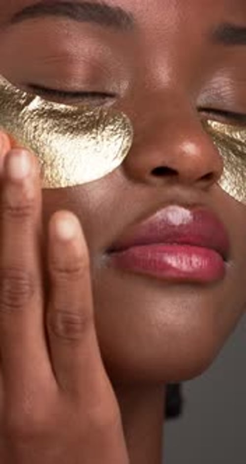 Black woman, skincare and eye mask in studio for moisturizer, gel and application on background
