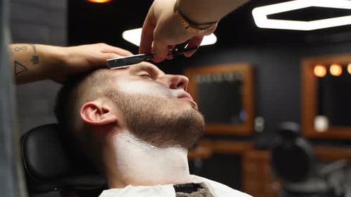 Stylish Shave: Young Man Getting Razor Shave at Barbershop