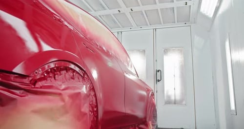 Red Car Being Painted in Automotive Paint Chamber
