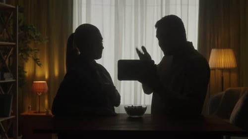 A Couple are Standing at the Table Watching a Video Film on a Tablet They Discuss What They Saw Eat