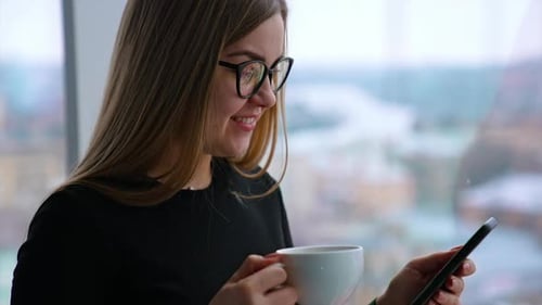 Young Woman Using Phone and Drinking Coffee