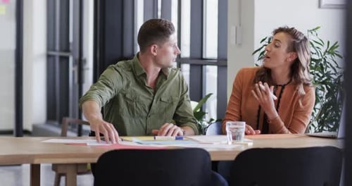 Diverse male and female colleagues in discussion using notes in casual office meeting