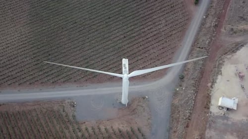 Aerial footage of Wind turbines spinning, in a mountain forest surrounding