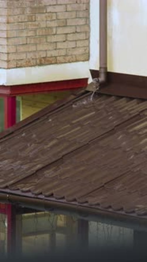 Rainwater Flows from Building Rooftop into Gutter