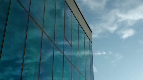 Reflexion von blauem Himmel und Wolken an der modernen Glasfassade.