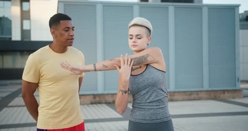 Man Assists Woman Stretching Arm Before Workout