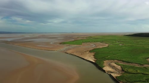 Wide aerial view of a costal bay at low tide, showing the natural pattens left behind, bright day.