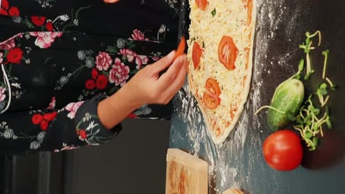Female chef hands adding tomatoes to pizza. Vertical video