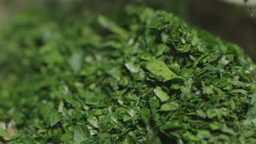 Chopped parsley is placed in a pan. Close up of preparing a delicious cafe de paris sauce.