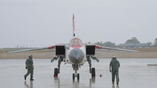 Men Working on Military Jet on Wet Tarmac