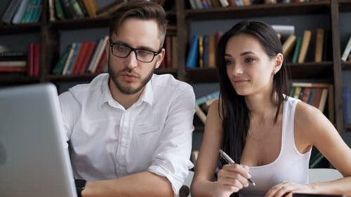 Two Students Brainstorm Work By Discuss With Desktop In Trendy Loft Close Up With Background Book...