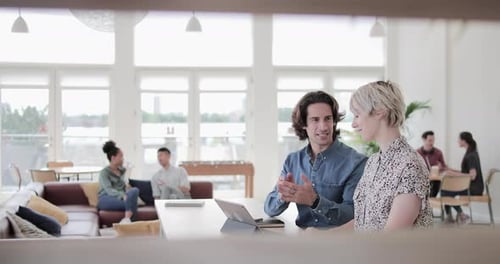 Two Adults Collaborate on Tablet in Modern Office