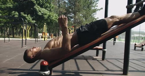 Muscular Man Works out Abs in Urban Park