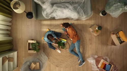 Top View Living Room Couple in New Apartment Woman Looking Through Stuff in Box Talking with Man
