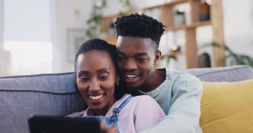 Smiling Couple Using Tablet at Home on Sofa