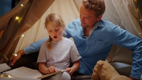 Father and Daughter Reading Together in Cozy Tent