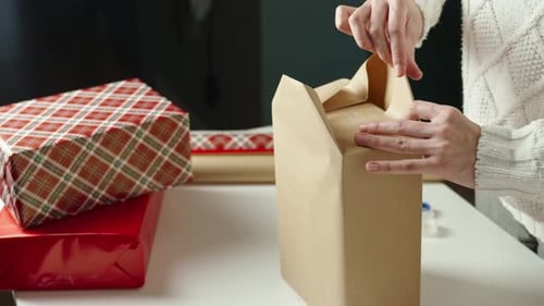 Hands Wrapping Christmas Gifts with Wrapping Paper