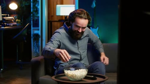 Overjoyed Man Sitting on Couch Laughing While Watching Funny Comedy Movie
