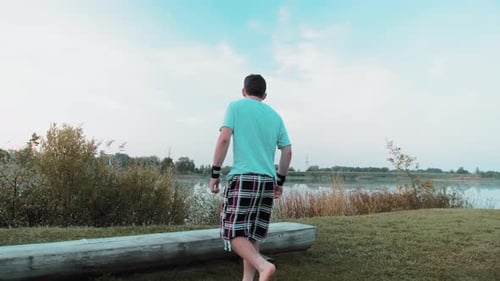 A Young Guy Enjoys Life At Dawn In Nature Behind A Lake Or A Quarry