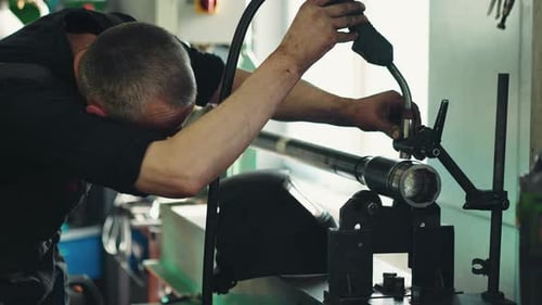 Mechanic performs maintenance and welding work of a propeller shaft in a car repair shop